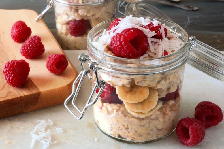 Healthy breakfast overnight oats with fresh raspberries and shredded coconut in a glass jar